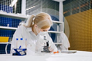 focused female science student looking in a microscope in a laboratory