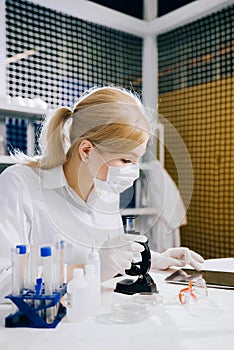 focused female science student looking in a microscope in a laboratory