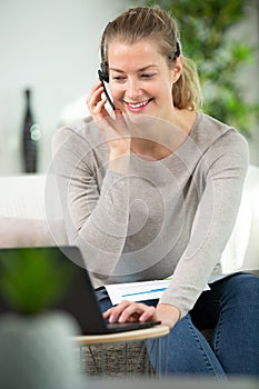 focused female on sofa wears headset and uses laptop