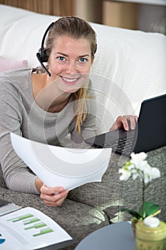 focused female wear headset sit on couch studying online