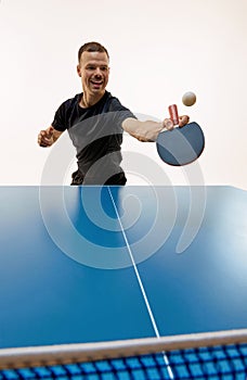 Focused on game, keeping eye on ping-pong ball sportsman, tennis player training in motion against white background.