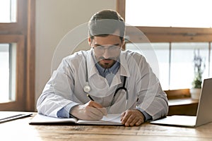 Focused general practitioner involved in paperwork in clinic office.