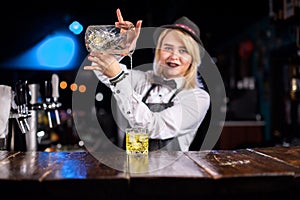 Focused girl bartending creates a cocktail while standing near the bar counter in pub