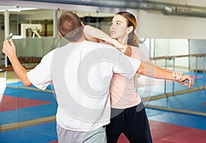 Girl performing elbow strike and wristlock to man in self defence training