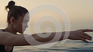 Focused girl reaching hands forward practicing yoga asana on seacoast.