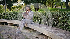 Focused girl reading book in sunlit park conveying peace. Woman enjoying leisure photo