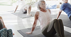 Focused group of unaltered diverse seniors practicing pilates on mats in sunny room, in slow motion