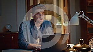 Focused guy browsing internet on pc at dark home closeup. Man typing laptop