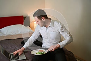 Focused guy using portable computer during lunch in aparthotel