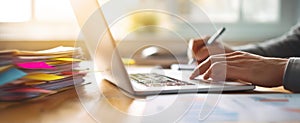 The focused hands working on a laptop with documents in a bright workspace.AI generated image