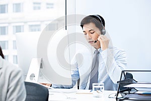 Handsome Asian man working in call center office as a telemarketing operator