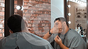 Focused handsome man shaving beard with razor