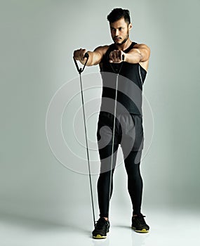 Focused on his workout routine. Studio shot of a young man working out with a resistance band against a gray background.