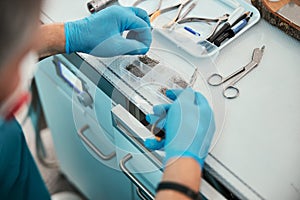 Focused image of unrecognized doctor choosing special device under the table