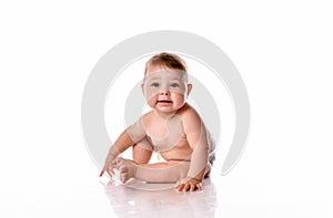 One year old baby girl sitting on white background.