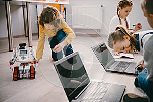 focused kids programming robots with computers while sitting
