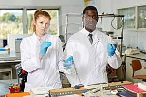 Focused lab technicians in gloves working with reagents and test tubes