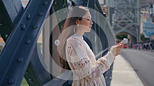 Focused lady surfing internet on smartphone leaning sunny iron bridge closeup