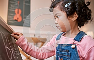 Focused on learning her alphabet. a little girl writing on a blackboard at home.