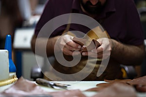 Leather craftsman at work shaping pieces into wallets in a busy workshop