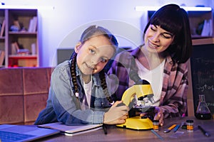 Focused little girl looking camera, working with electron microscope.