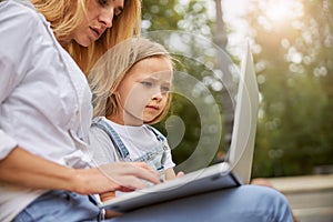 Focused little miss sitting in the park with mother