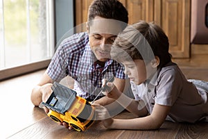 Focused little son fix toy car with help of daddy