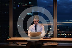 Focused male employee develop project by laptop late at evening