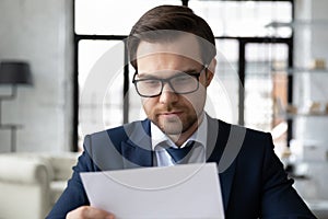 Focused male employer read paper letter in office