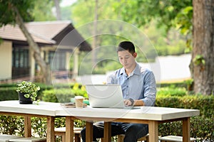 Focused male freelancer working with laptop on table at outdoor cafe