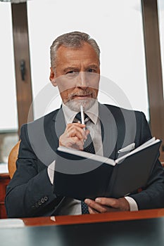 Focused Male hotelier making notes in diary while sitting in his office in hotel