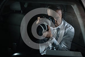 focused male private detective in headphones doing surveillance by camera