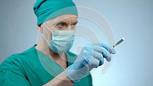 Focused male surgeon holding sharp scalpel in hand, ready to start surgery