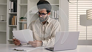 Focused man Arabian Indian ethnic businessman male employee manager writing notes business tasks data paperwork signing