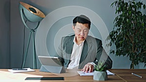 Focused man diligently operating tablet and using stylus in indoors workspace