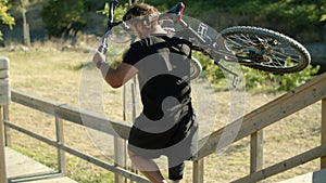 Focused man with disability lifting bike and going down stairs