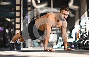 Focused man doing mid-push-up exercise while training at gym