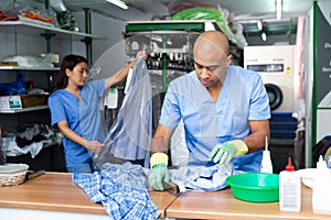Focused man drycleaner removing spots and stains