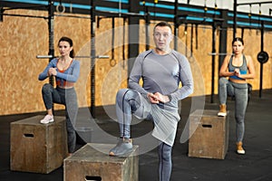 Focused man executing step-up exercises on plyo box at gym