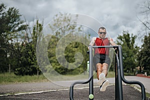 Focused man exercising on horizontal bars in lush green park
