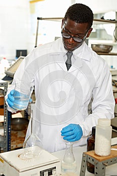 Focused man lab technician in glasses working with reagents and test tubes