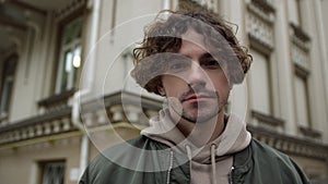 Focused man looking camera on street. Cool guy posing on city background.