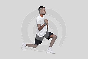 Focused man lunging for exercise on gray background