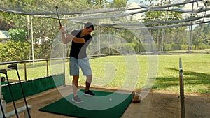 Focused man practicing golf swing on