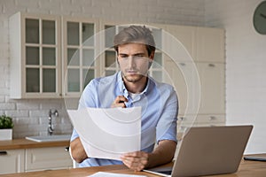 Focused man reading letter, working with correspondence at home