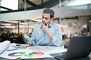 Man Analyzing Color Palettes While Working on Design Projects in a Modern Office Space During Daytime