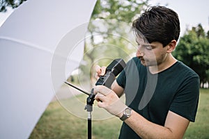 Focused man setting umbrella flash to light stand