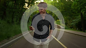 Focused man texting message outdoors. Handsome guy using smartphone in park