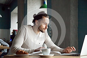 Focused man writing notes learning online with laptop in cafe photo