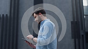 Focused manager using tablet computer at modern office building. App user.